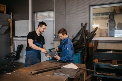 Arbeiter messen gemeinsam ein Metallstück.