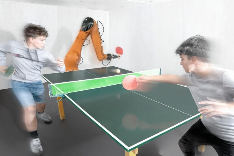 Zwei Jungen spielen einen Tischtennis-Rundgang mit einem Industrieroboter.7