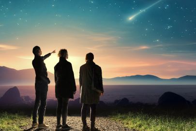 Familie steht in der Nacht auf Weg und beobachtet eine Sternschnuppe