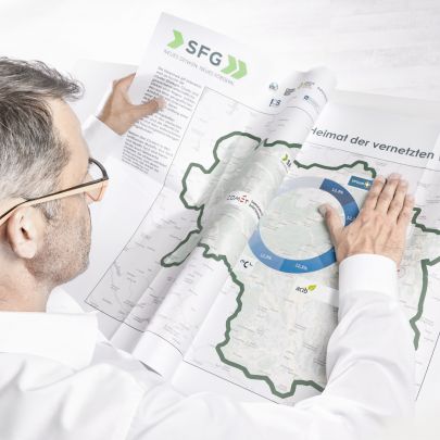 Mann streicht Zeitung mit Steiermark-Landkarte glatt