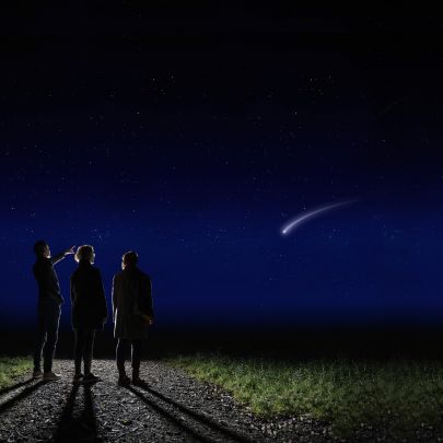 Familie steht in der Nacht auf Weg und beobachtet eine Sternschnuppe