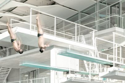 Zwei Männer springen in Hallenbad von 5-Meter-Turm