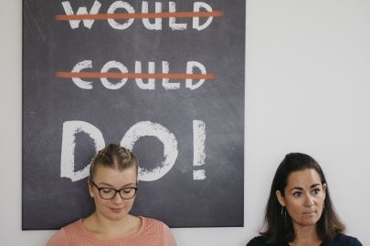 2 Frauen sitzten vor Plakat