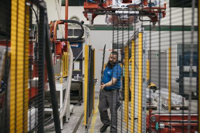 Mann trägt in Produktionshalle Metallgitter