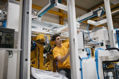 Junger Mann im gelben Shirt arbeitet an Maschine