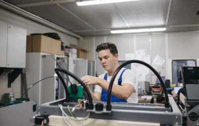 Junger Mann in blauer Latzhose arbeitet an Maschine