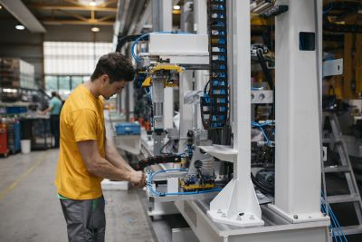 Junger Mann im gelben T-Shirt arbeitet an Maschine