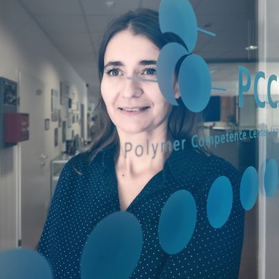 Frau steht hinter Glastür mit der Aufschrift PCCL und runden blauen Kreisen