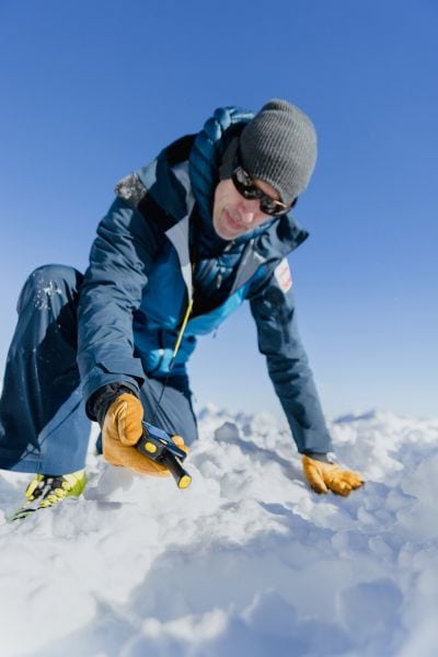 Mann im Schnee mit Lawinenverschüttetenmessgerät